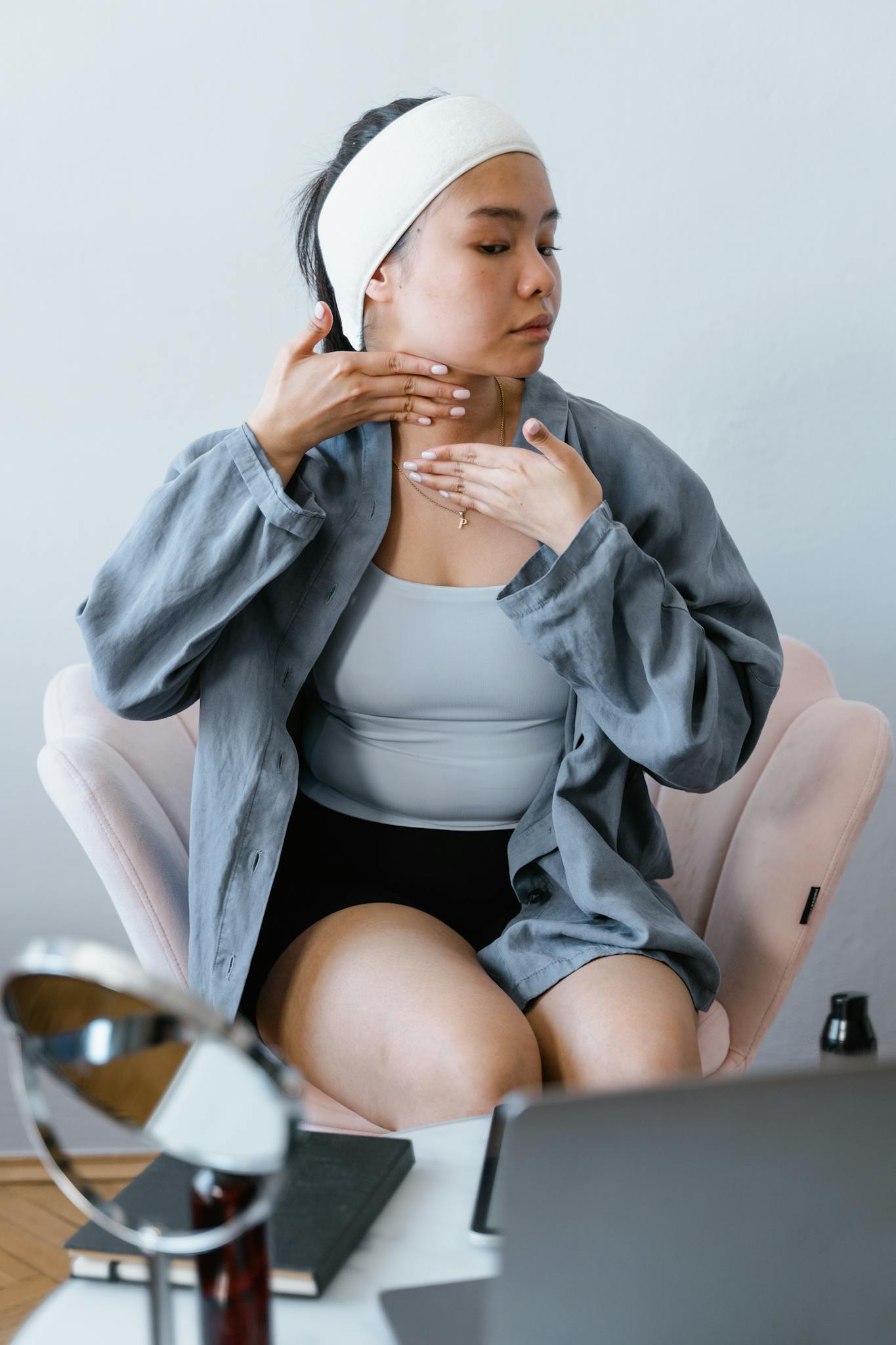 Asian woman applying skincare routine seated, emphasizing self-care and relaxation.