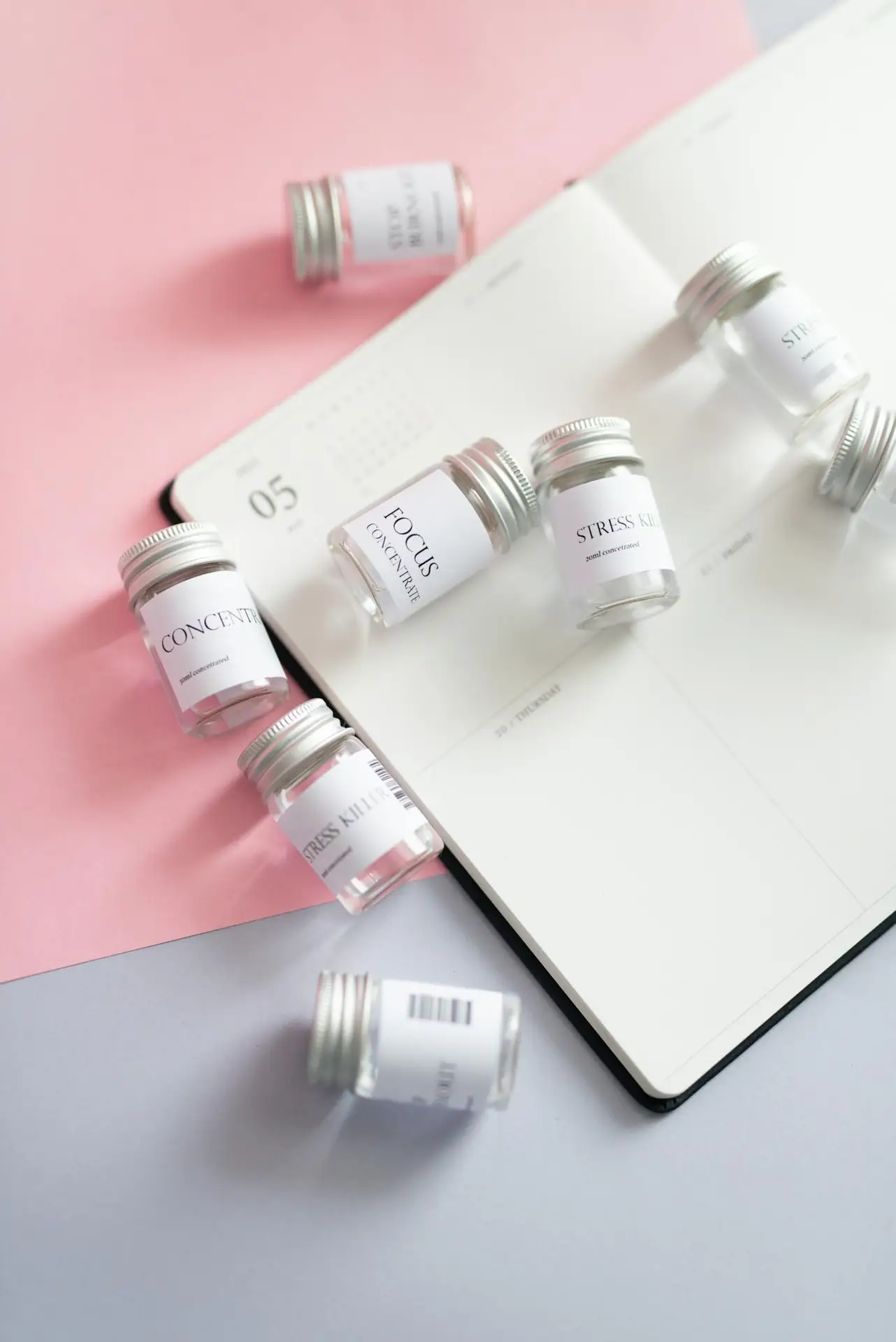 Glass jars labeled for stress relief on a planner with pink accent paper, creating a minimal still life.