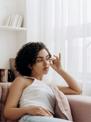 Young woman relaxing on a couch, embodying beauty and tranquility in a light-filled room.