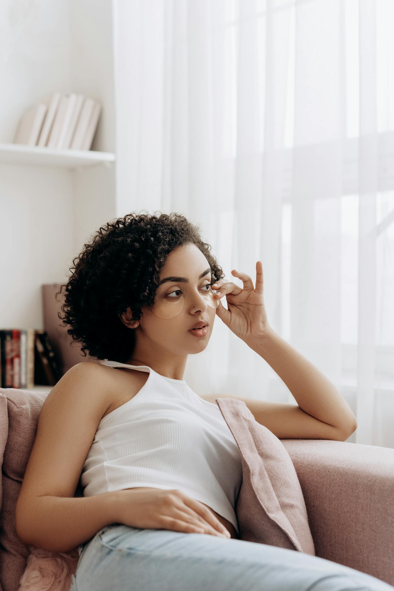 Young woman relaxing on a couch, embodying beauty and tranquility in a light-filled room.
